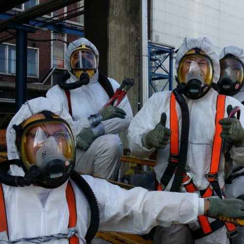 Crew in protective clothing with full-face masks on an industrial site