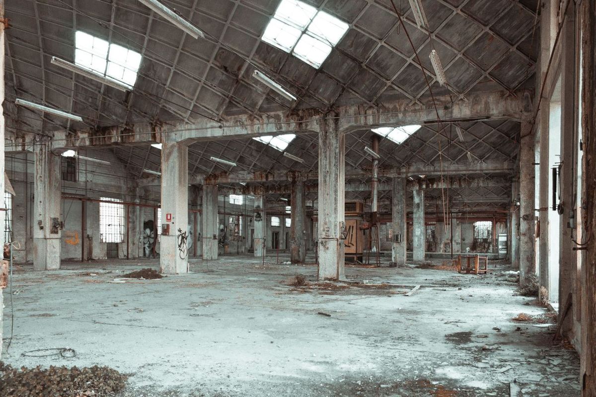 Hall industriel désaffecté avec colonnes en béton et lanterneaux