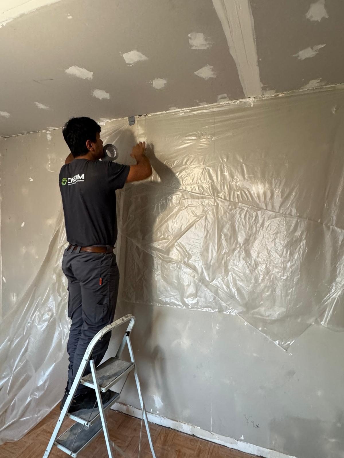 Credim worker taping sheeting while setting up a hermetic zone