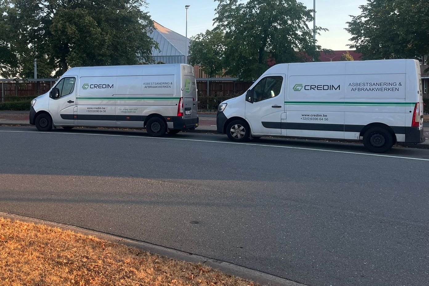 Two Credim vans parked at the roadside in front of trees