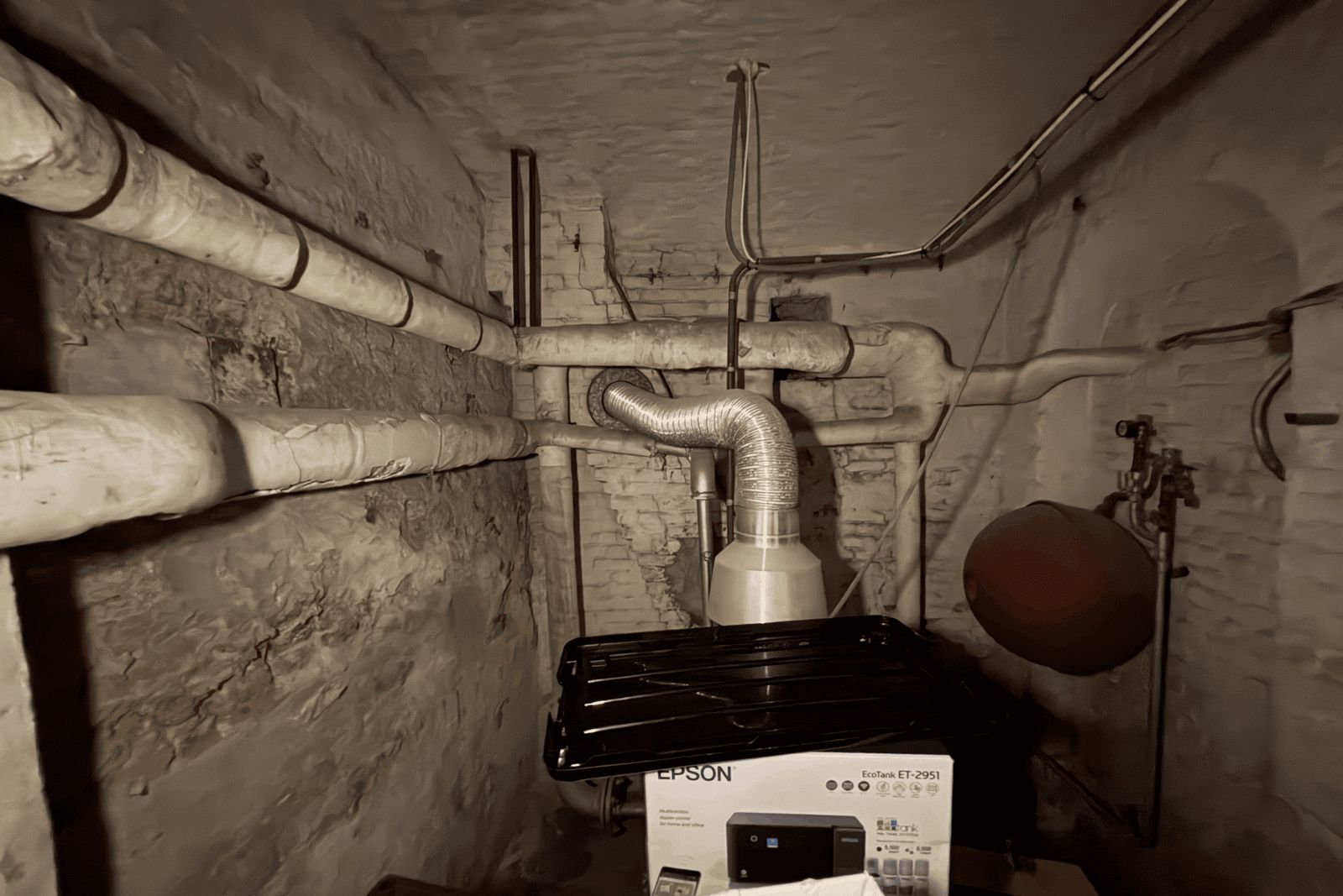 Cave voûtée avec des conduites isolées le long du mur et une gaine flexible argentée