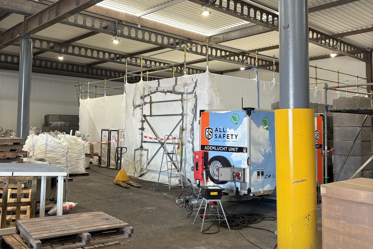 Hermetic zone of white sheeting with scaffolding in an industrial hall