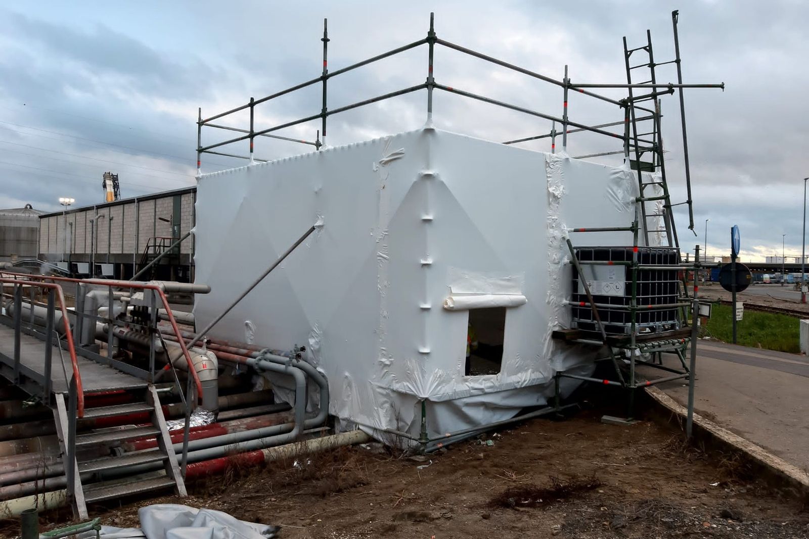 Hermetic zone in white sheeting with scaffolding on an industrial site, for removing pipe insulation