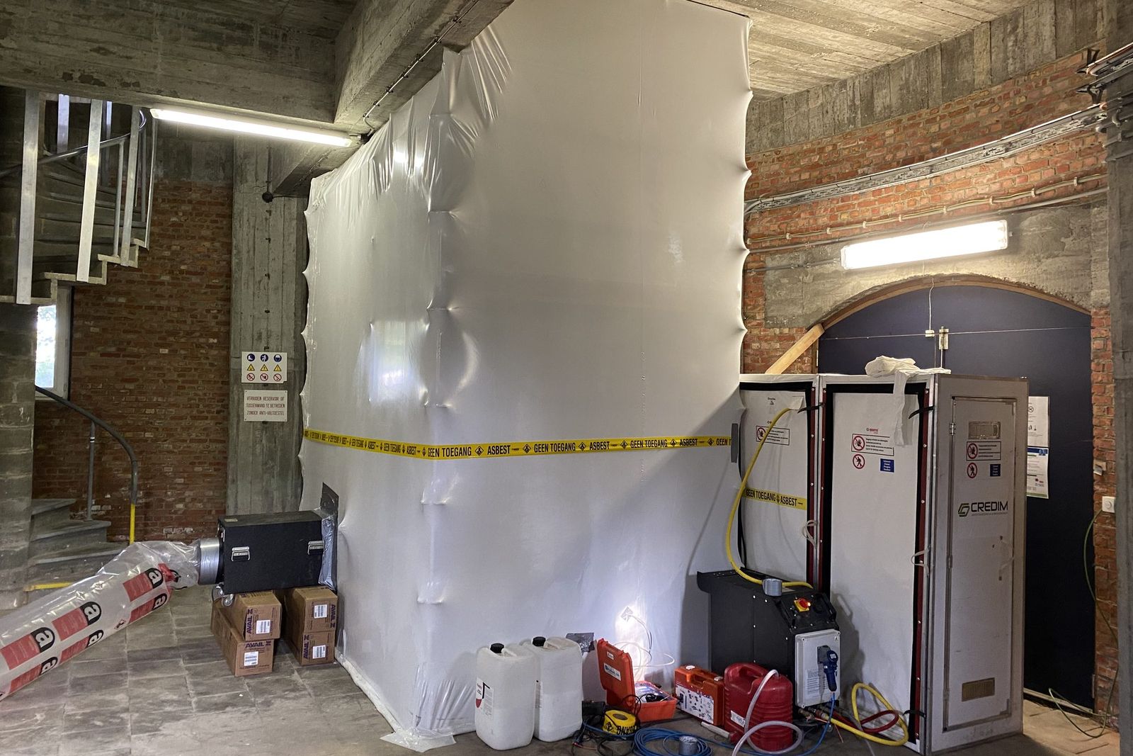 Hermetic zone of white sheeting with asbestos warning tape in a water tower