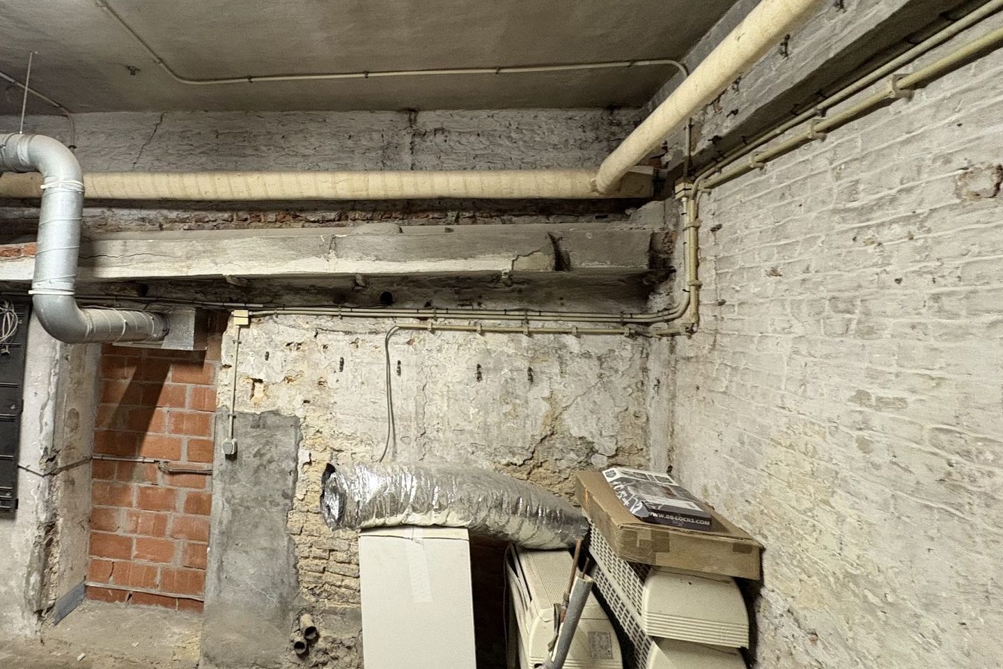 Conduite isolée le long du plafond, dans le coin d'une pièce aux vieux murs de briques