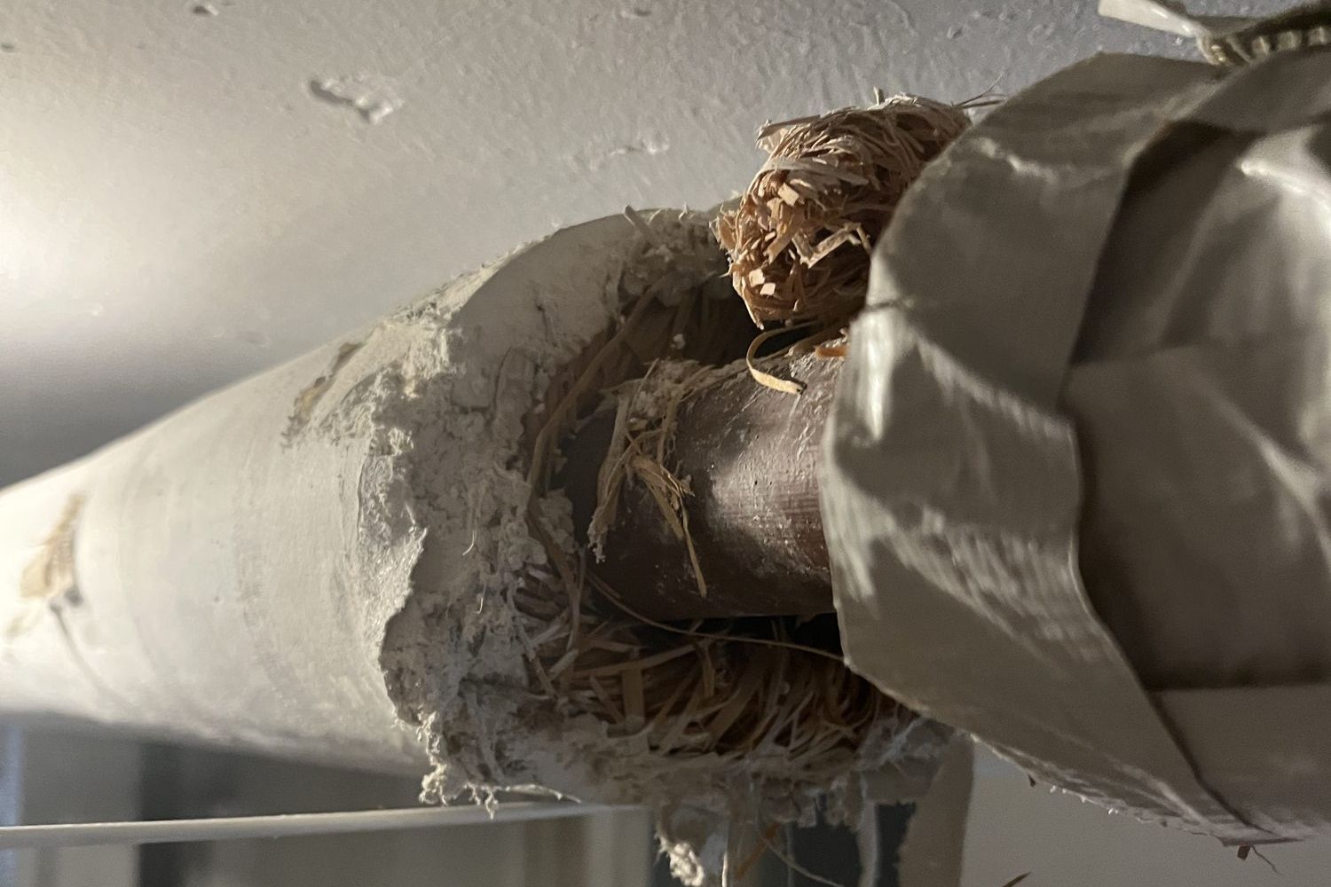 Close-up of damaged pipe insulation with the fibrous material exposed