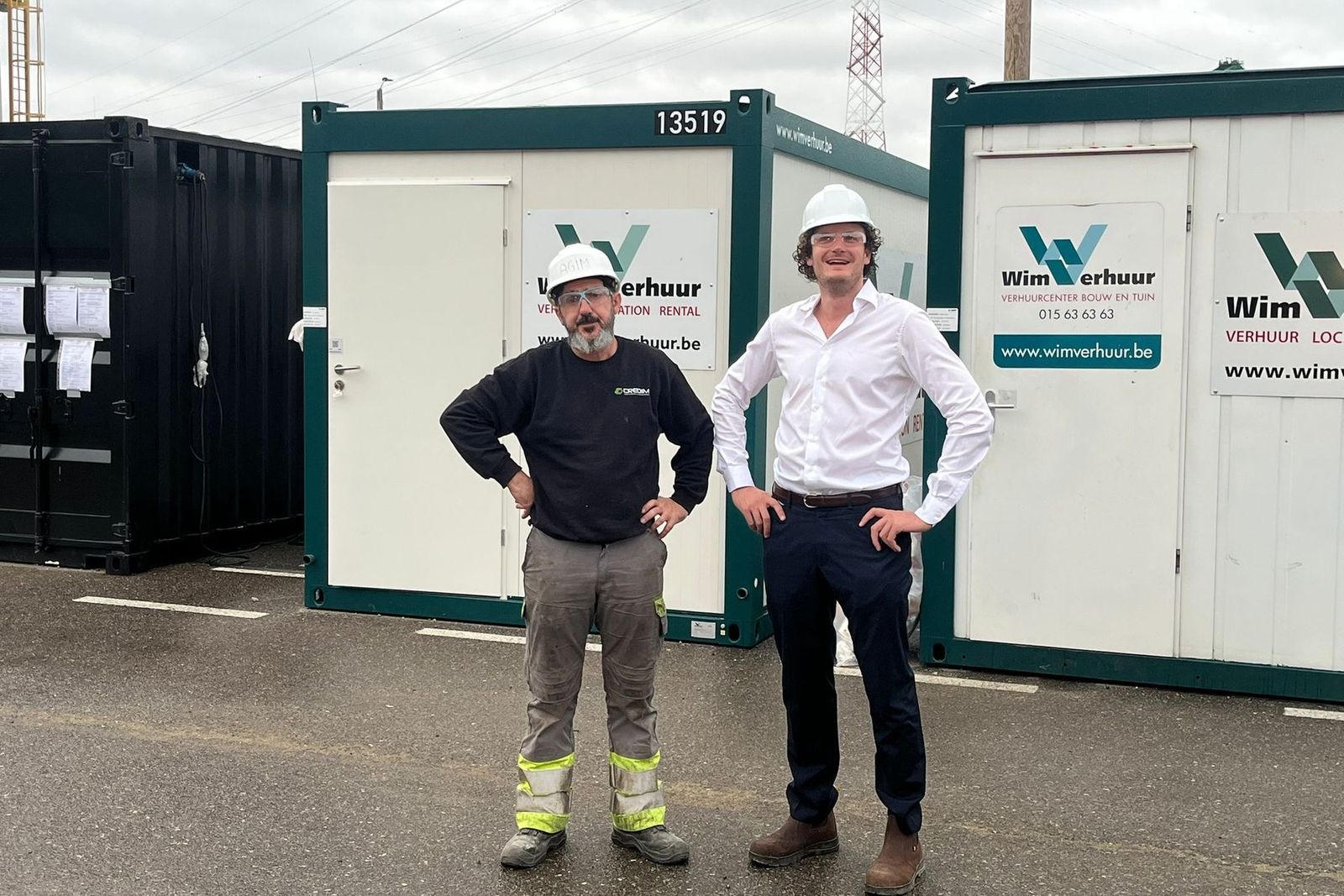 Two Credim staff in hard hats in front of site containers