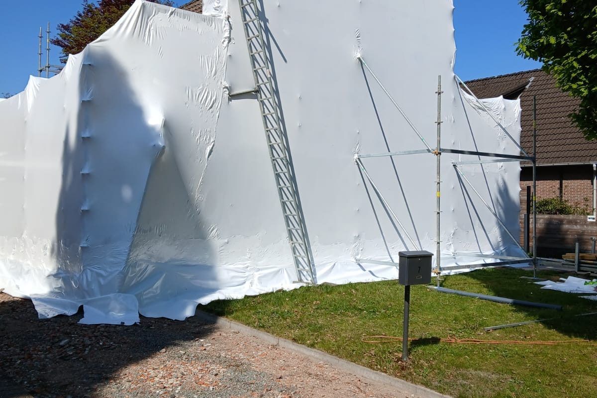 Hermetische zone rond een hele woning, ingepakt in witte folie met steigers