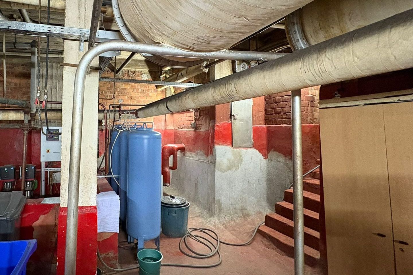 Conduites isolées sous le plafond, au-dessus de cuves bleues et d'un escalier