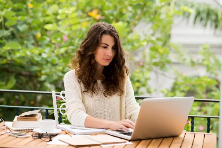 Vrouw werkt als freelance tekstschrijver op laptop in groene buitenomgeving