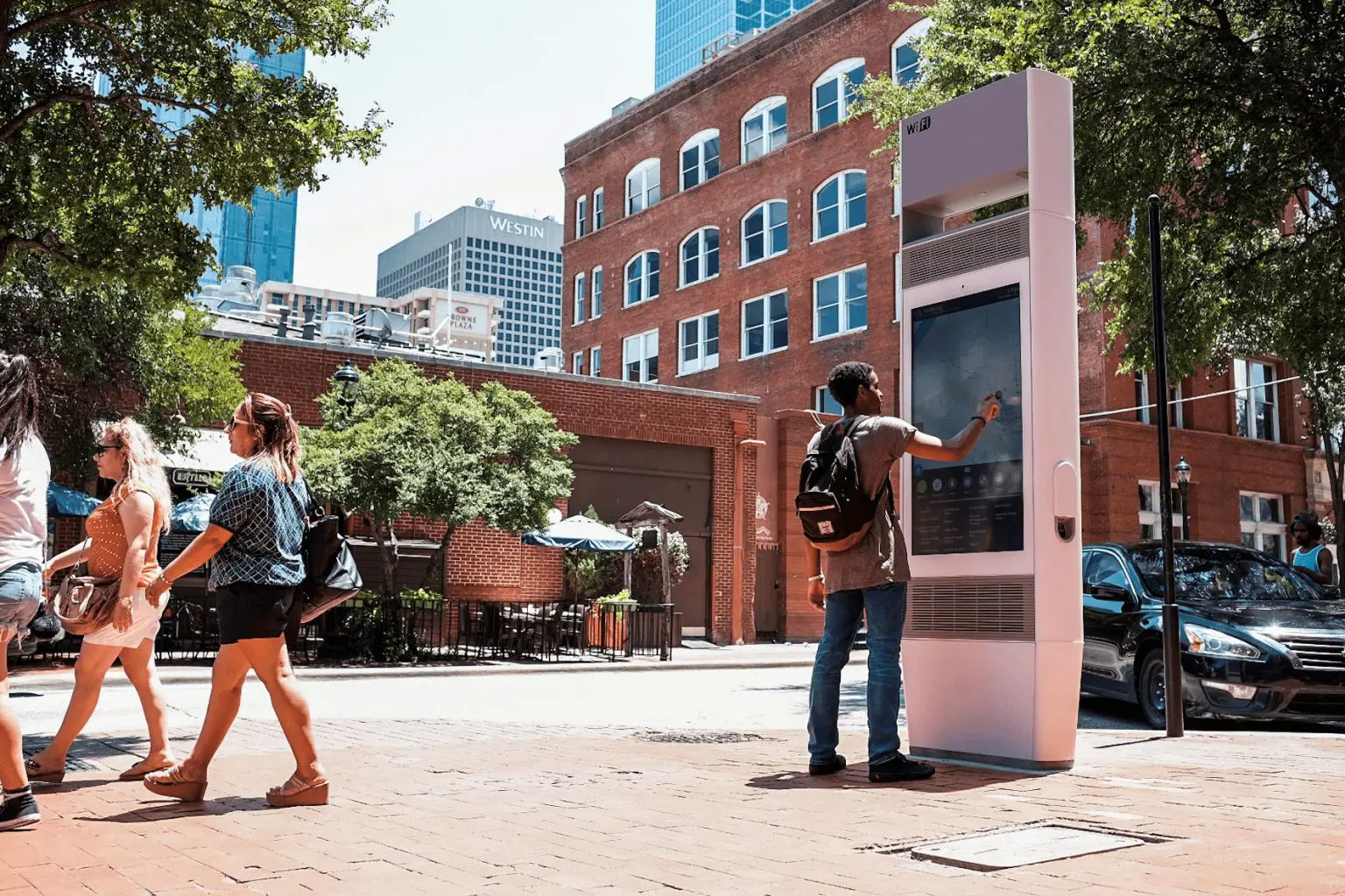 Man gebruikt interactieve digitale zuil op druk stadsplein met voorbijgangers