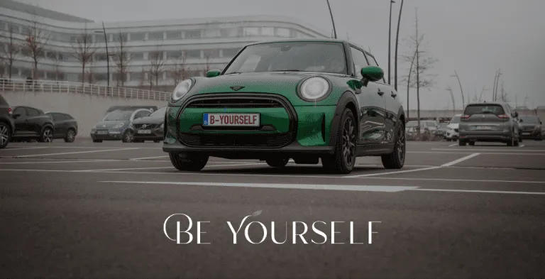 Groene MINI Cooper geparkeerd op parkeerplaats met tekst Be Yourself