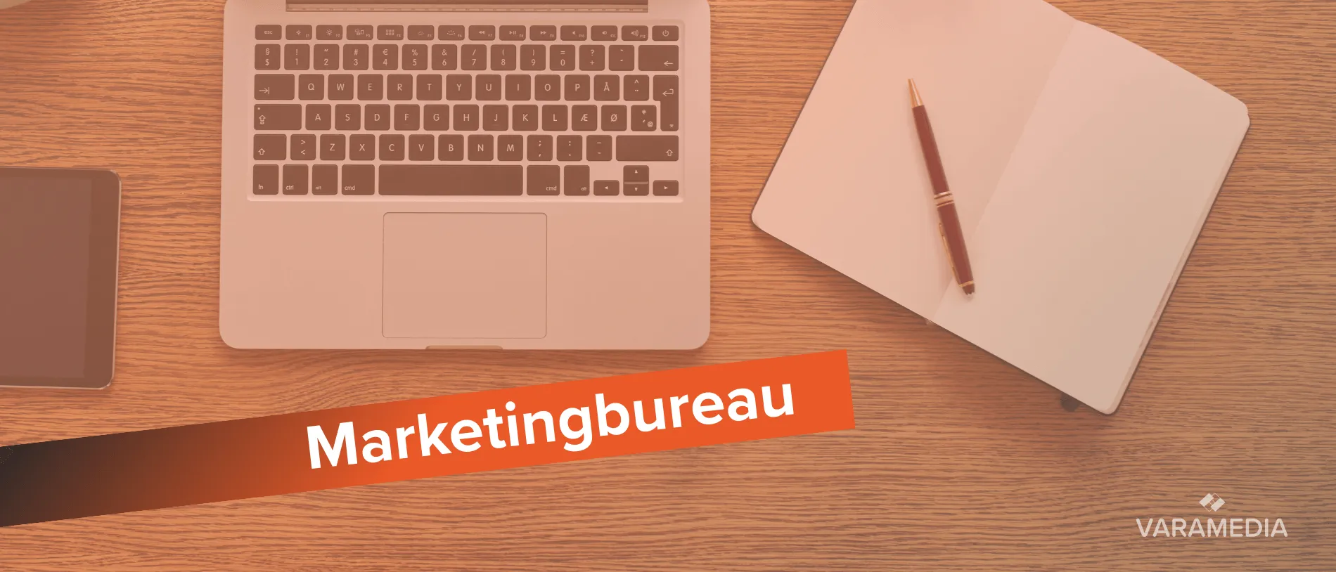 Laptop en notitieboek op houten bureau met tekst marketingbureau