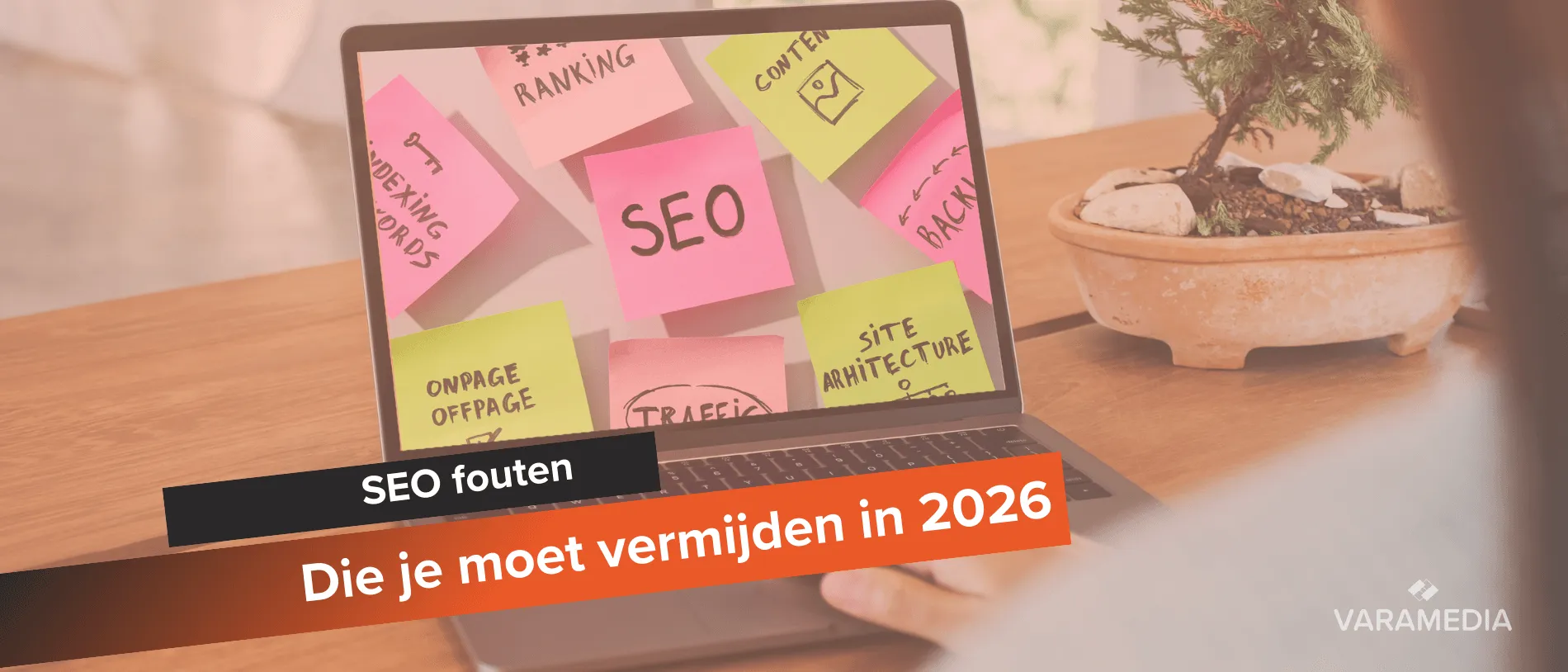 Laptop met roze post-its over SEO-termen zoals ranking en traffic